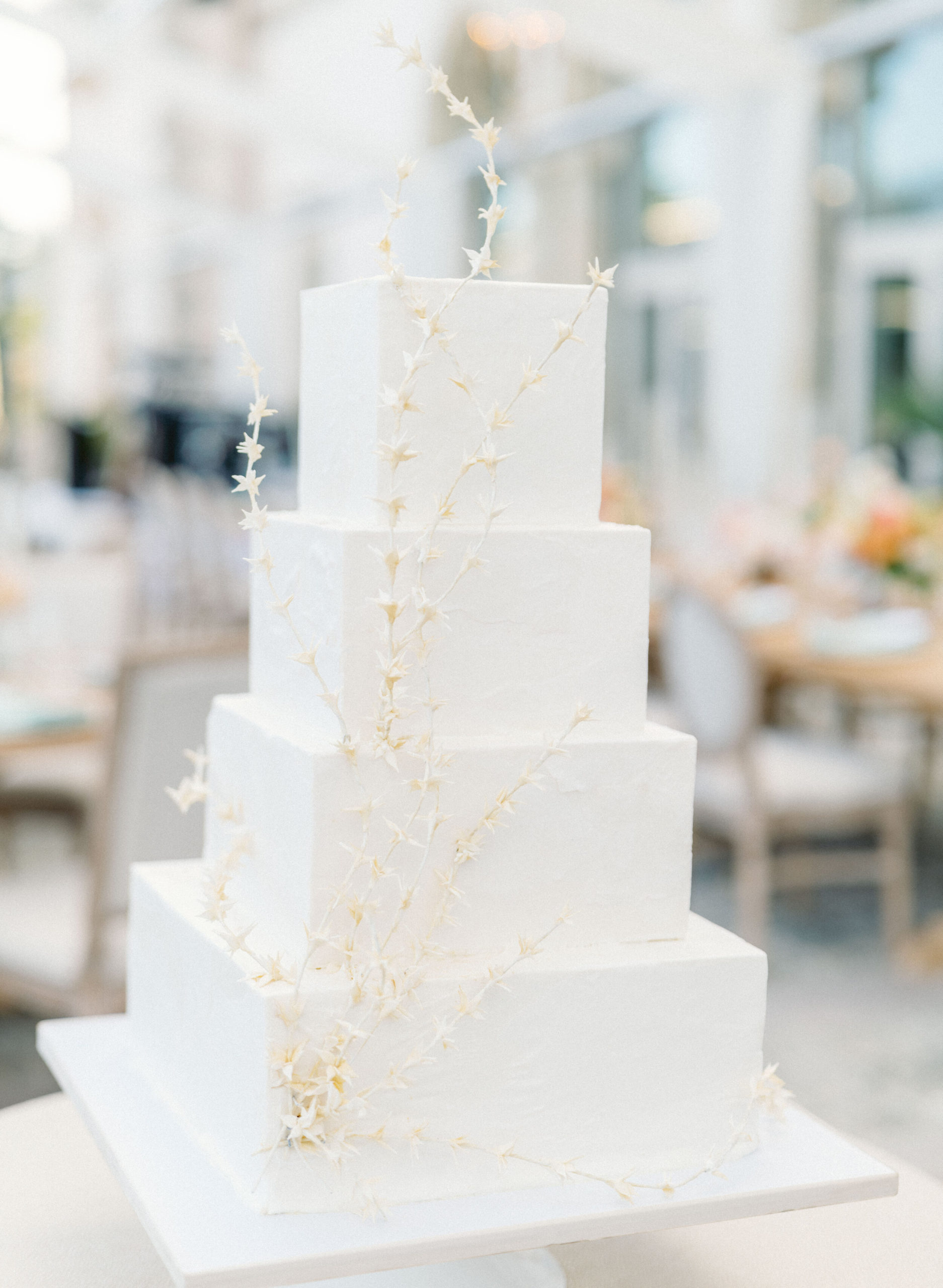 white, four tier square wedding cake with dried floral accent