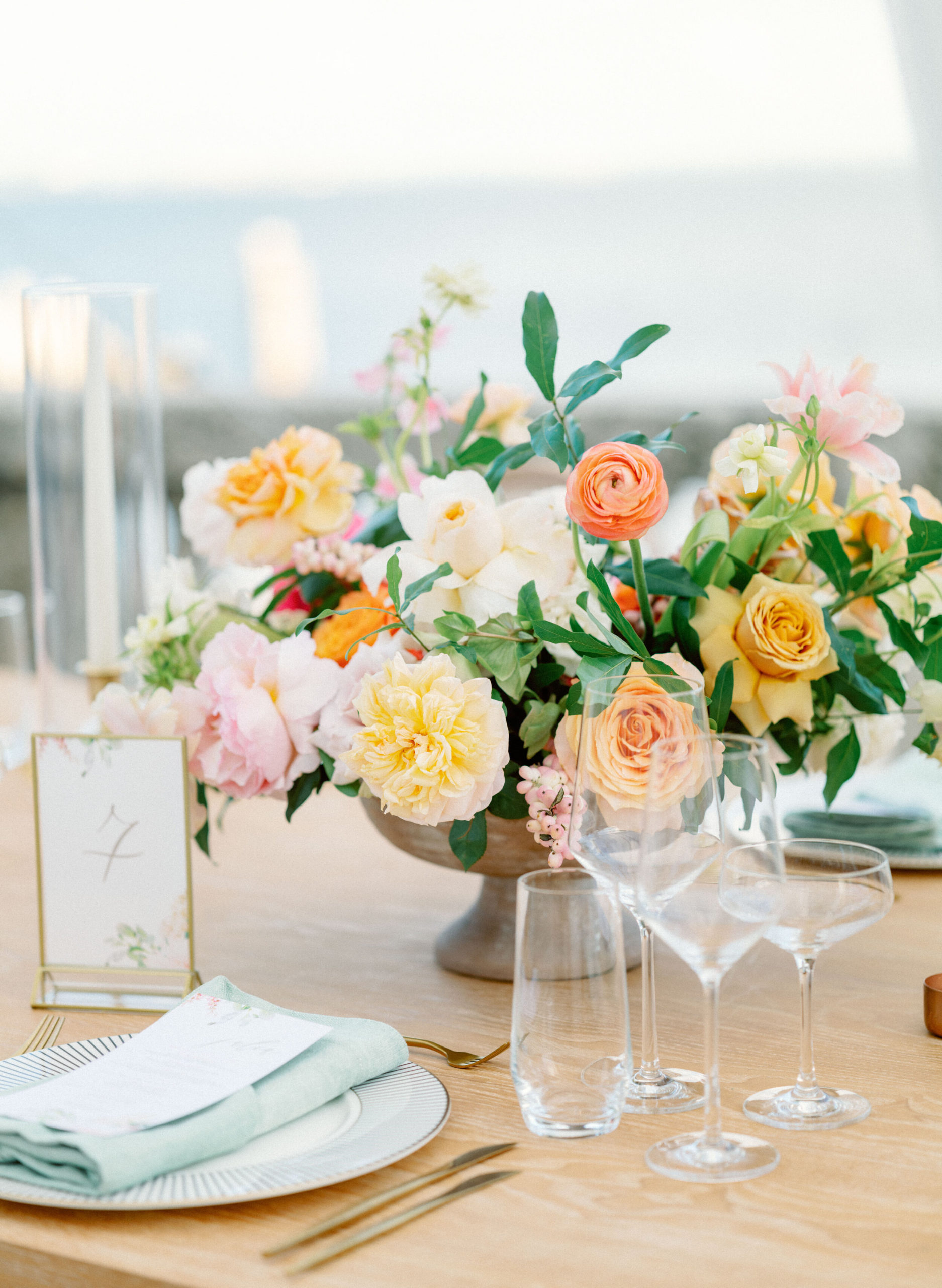 floral centerpiece with peonies and ranunculus in peach, pink and yellow. 