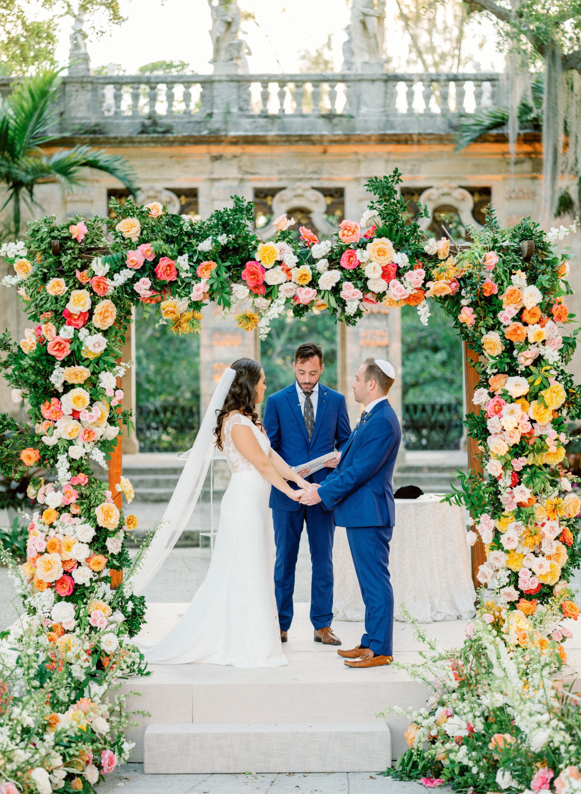 jewish wedding ceremony beneath colorful floral chuppah at Vizcaya Museum
