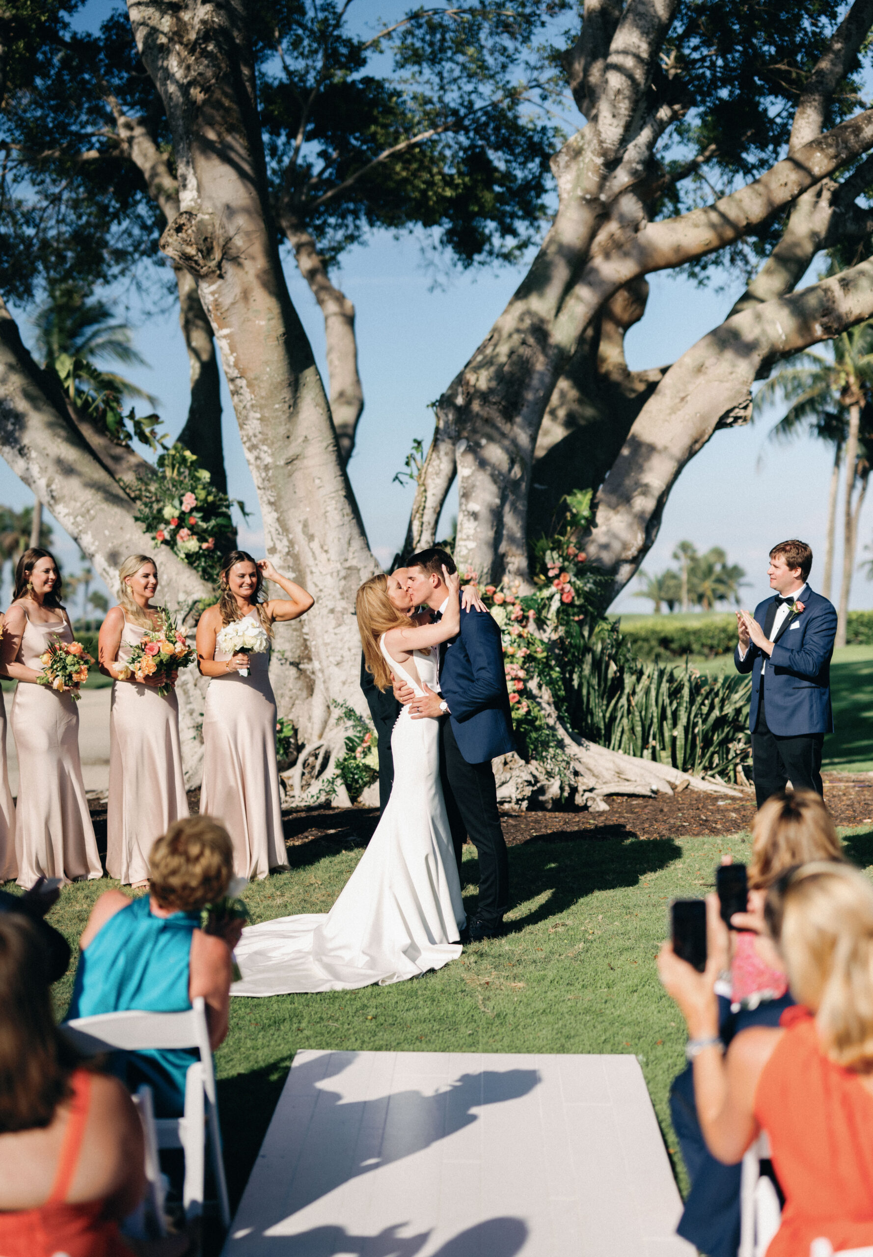 bride and groom kiss at the alter, under massive tree