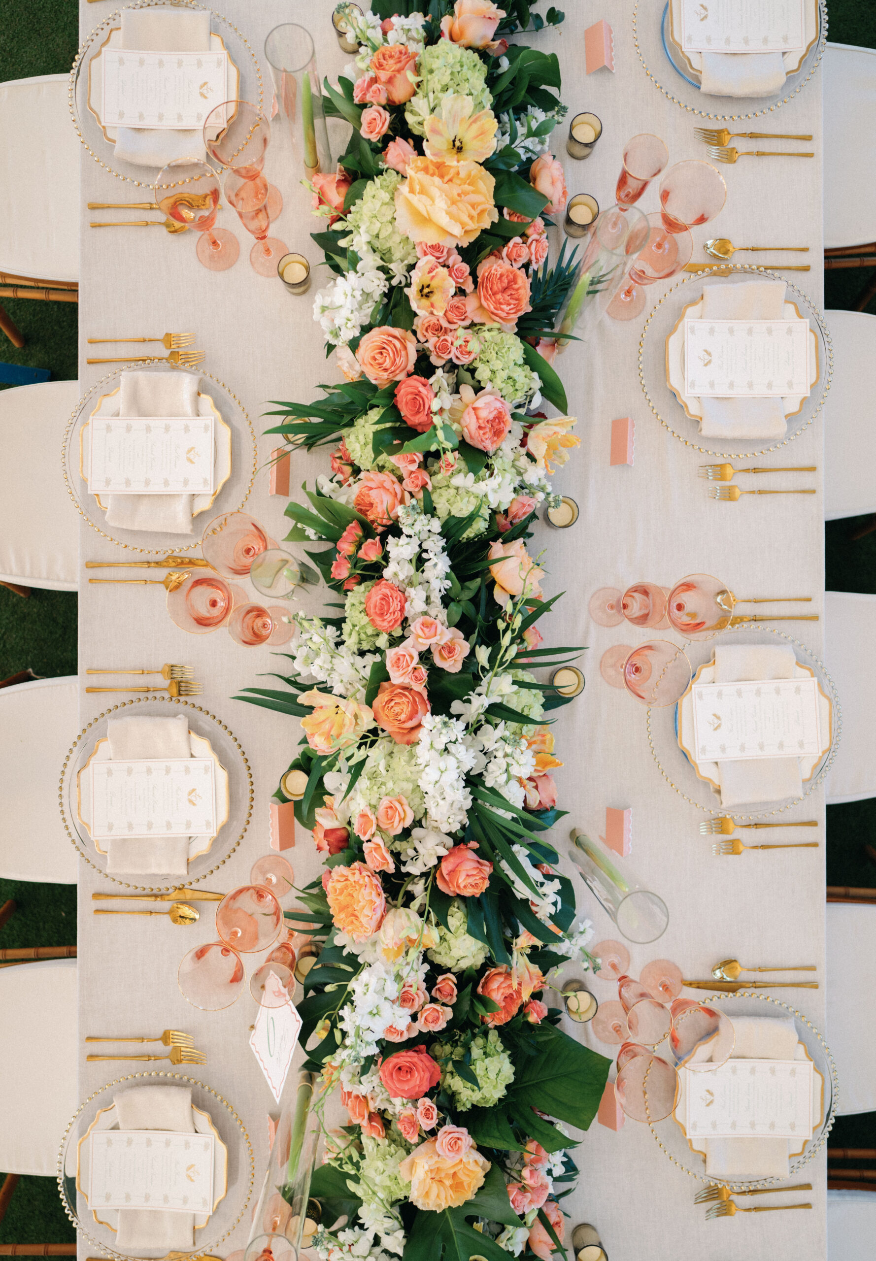 wide, top down tabletop view of floral garland in peach, coral and green