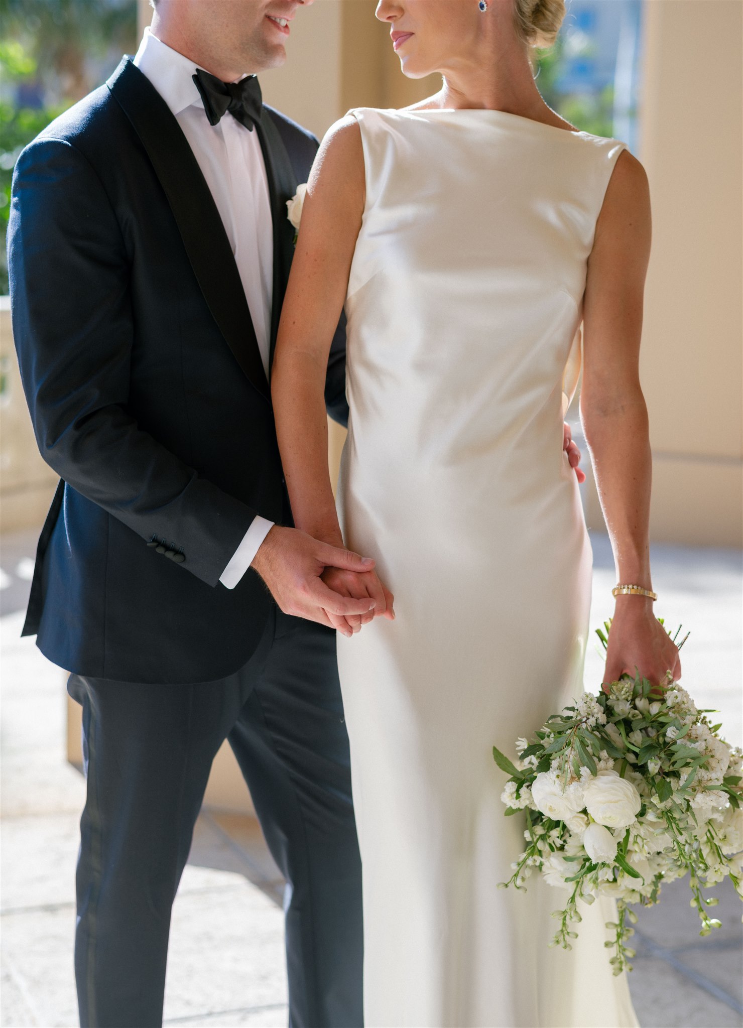 Groom holding bride's hand in a-line silk gown