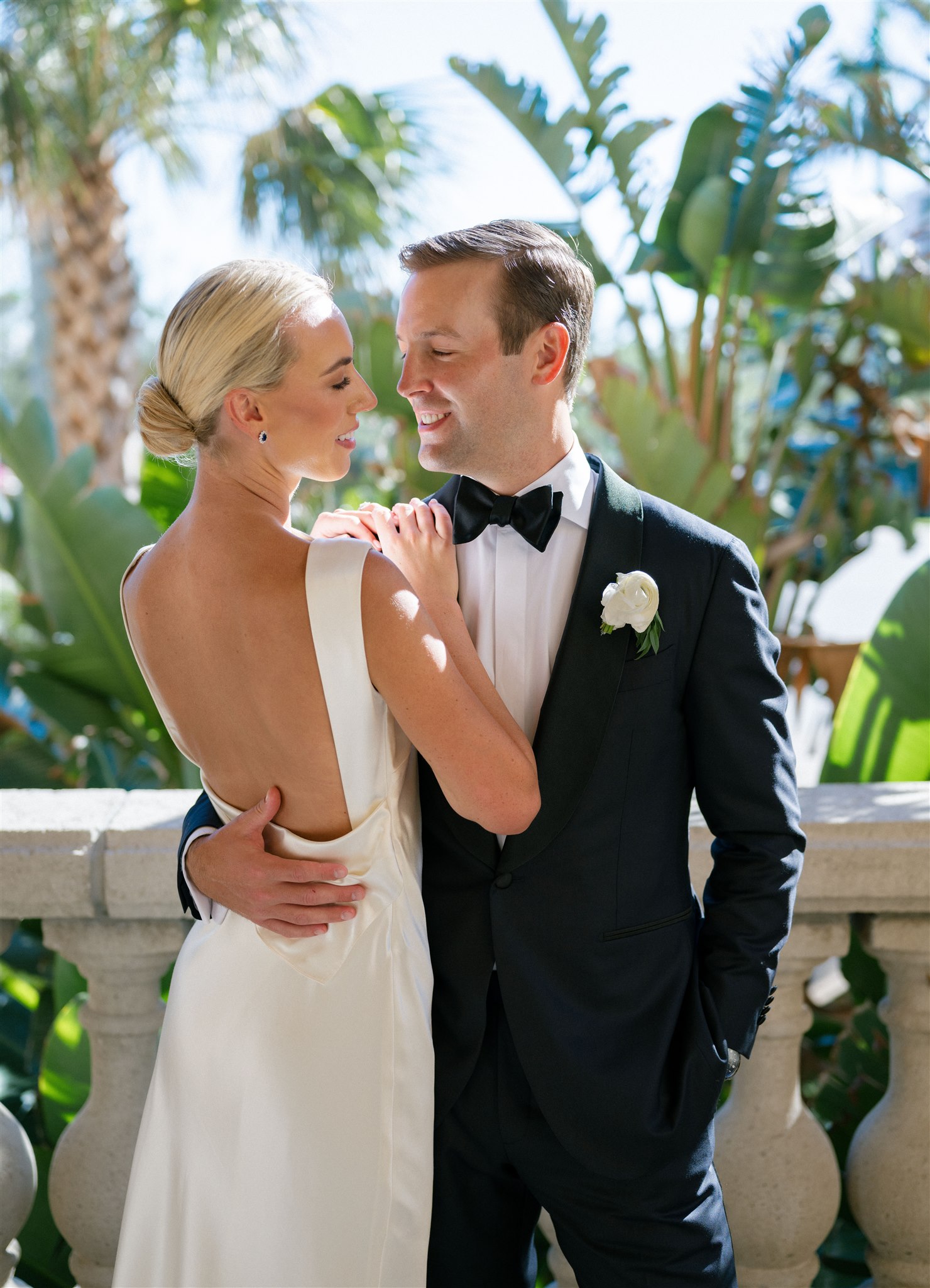 A bride and groom take wedding portraits under the palm trees at the Ritz Carlton in Florida.