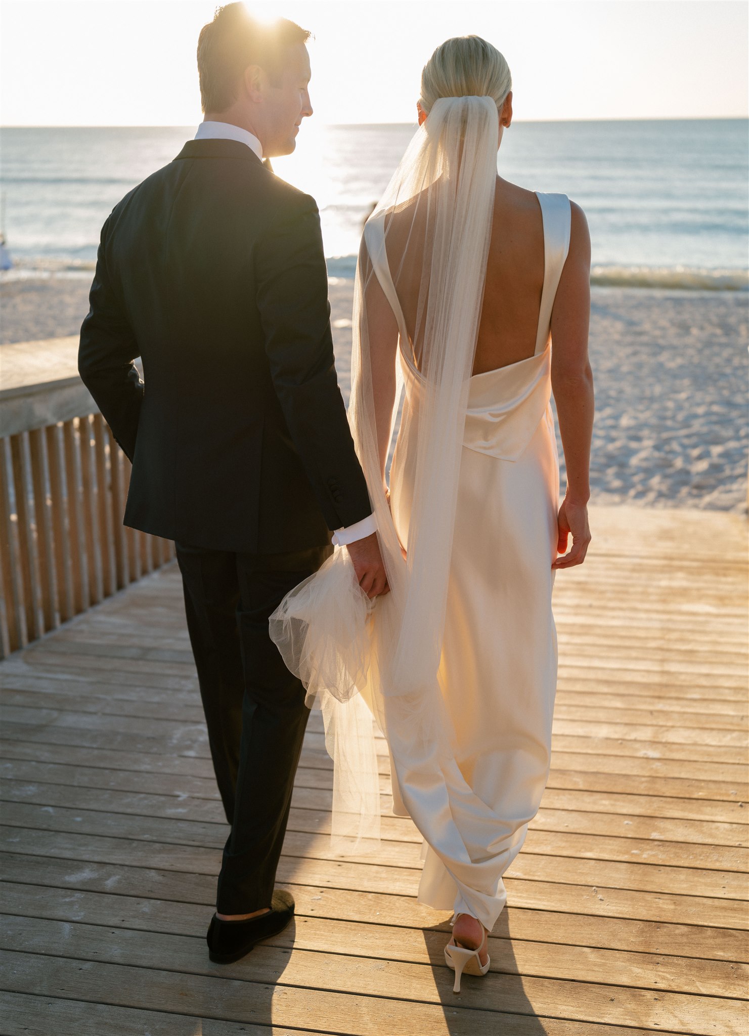 Groom holding bride's dress on Naples, FL beach