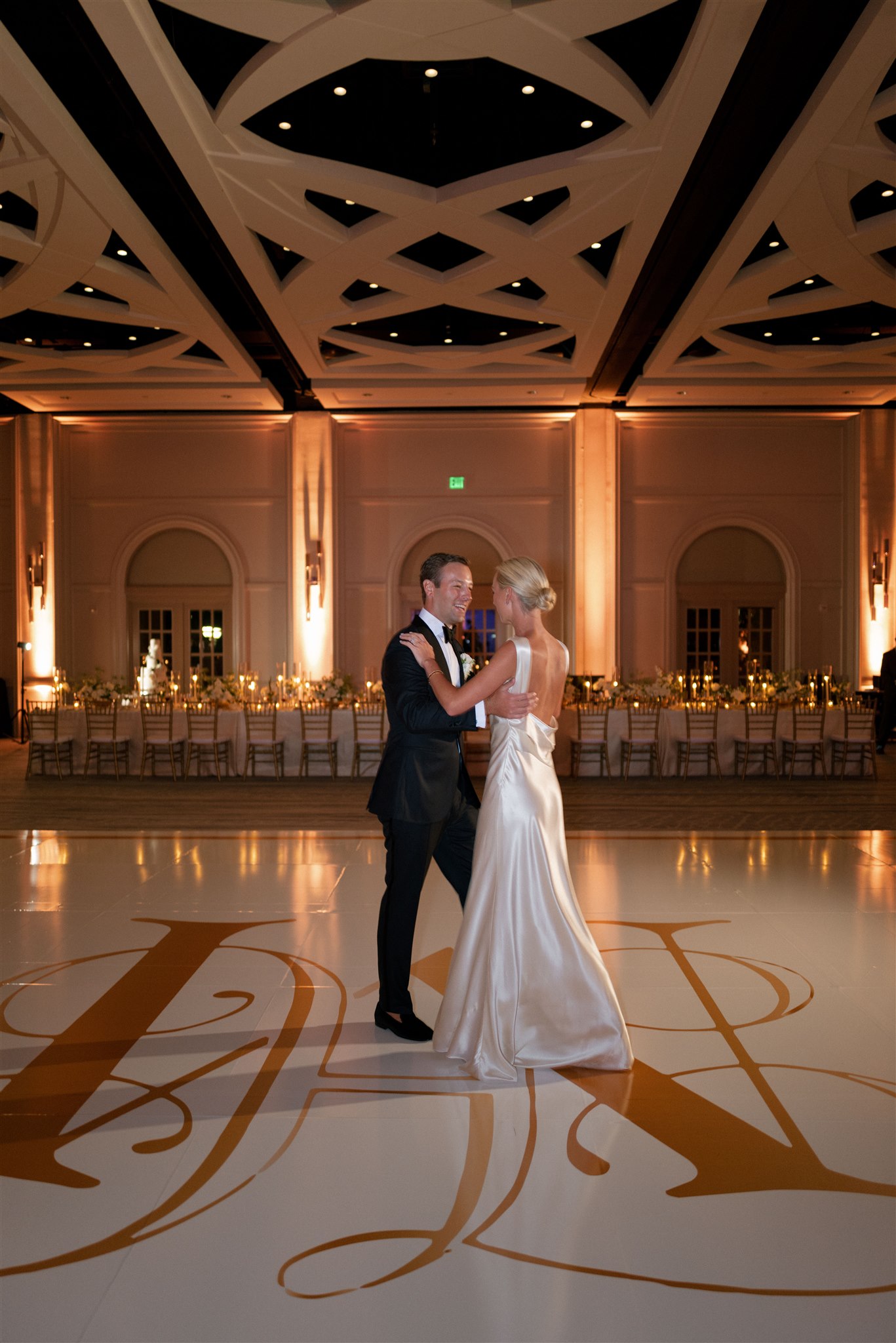 Private first dance on custom white dance floor with gold monogram