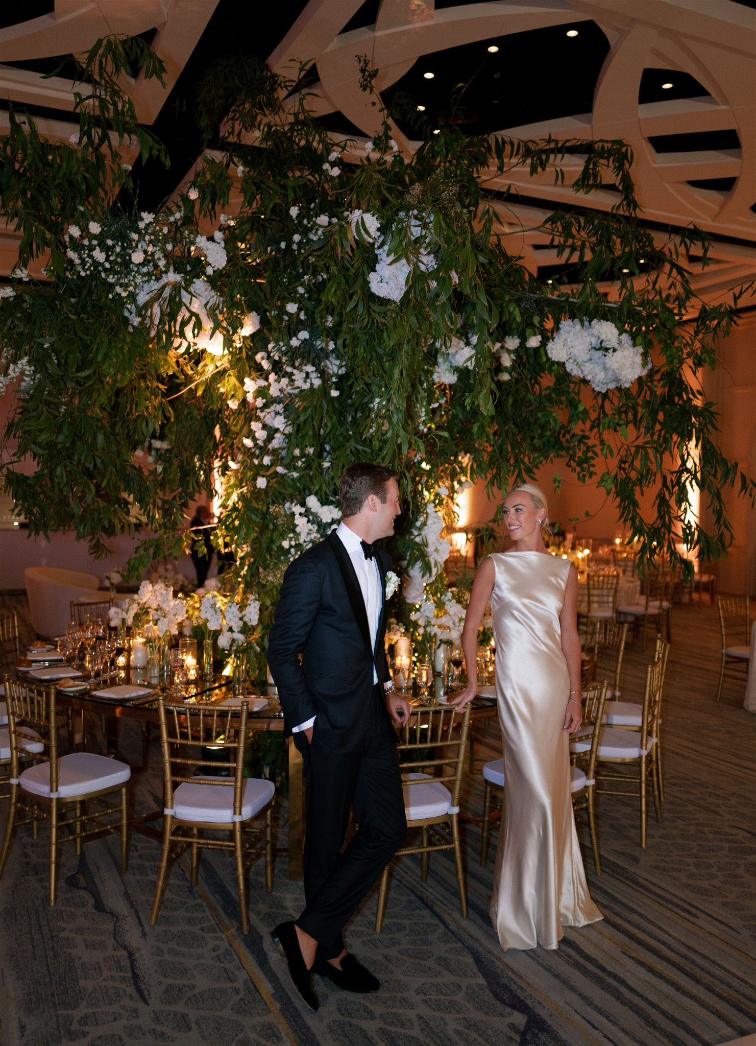 Bride and groom in front of fabricated greenery tree at wedding reception