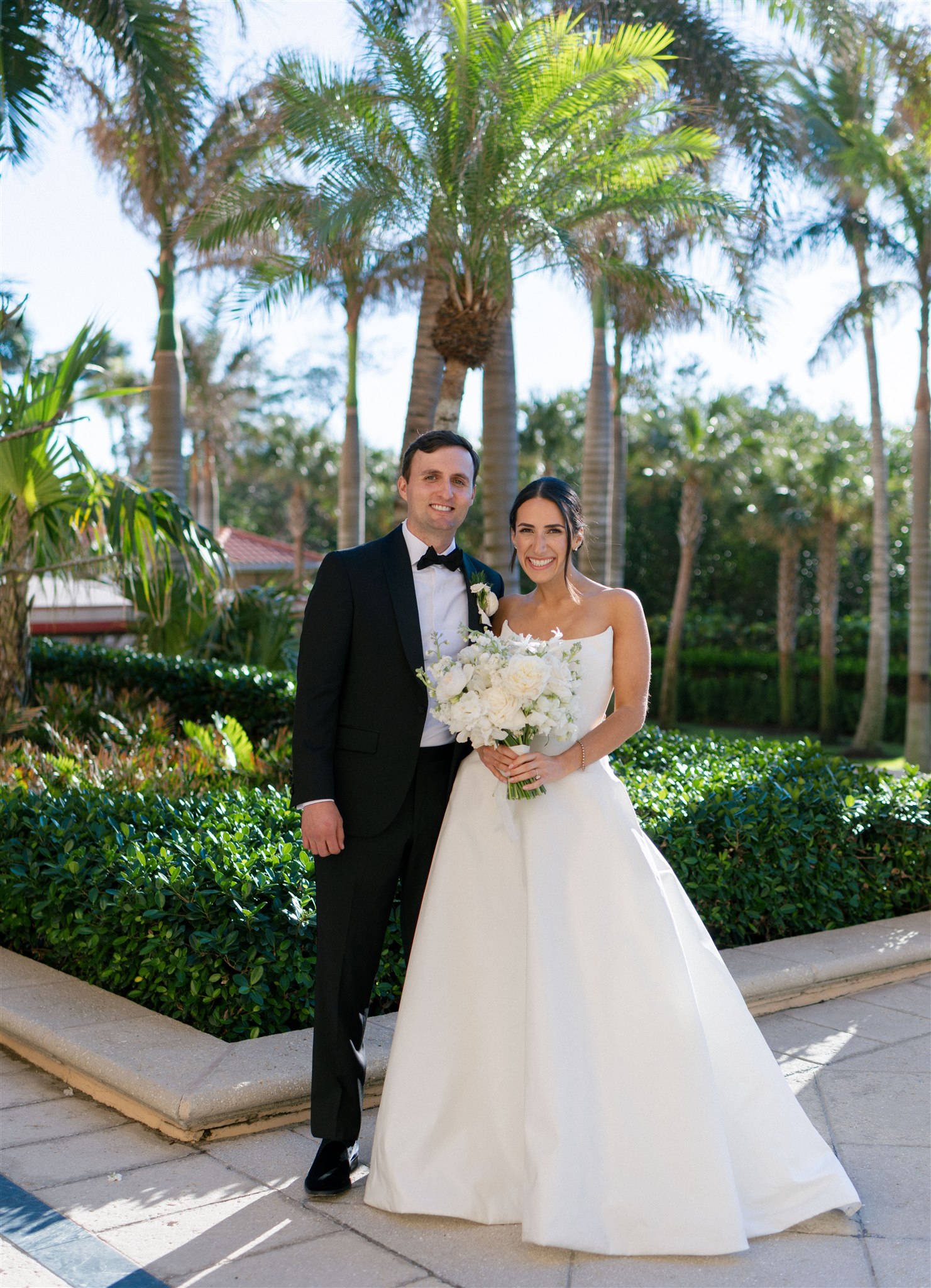 A bride and groom poses under the palm trees in Florida on their wedding day.