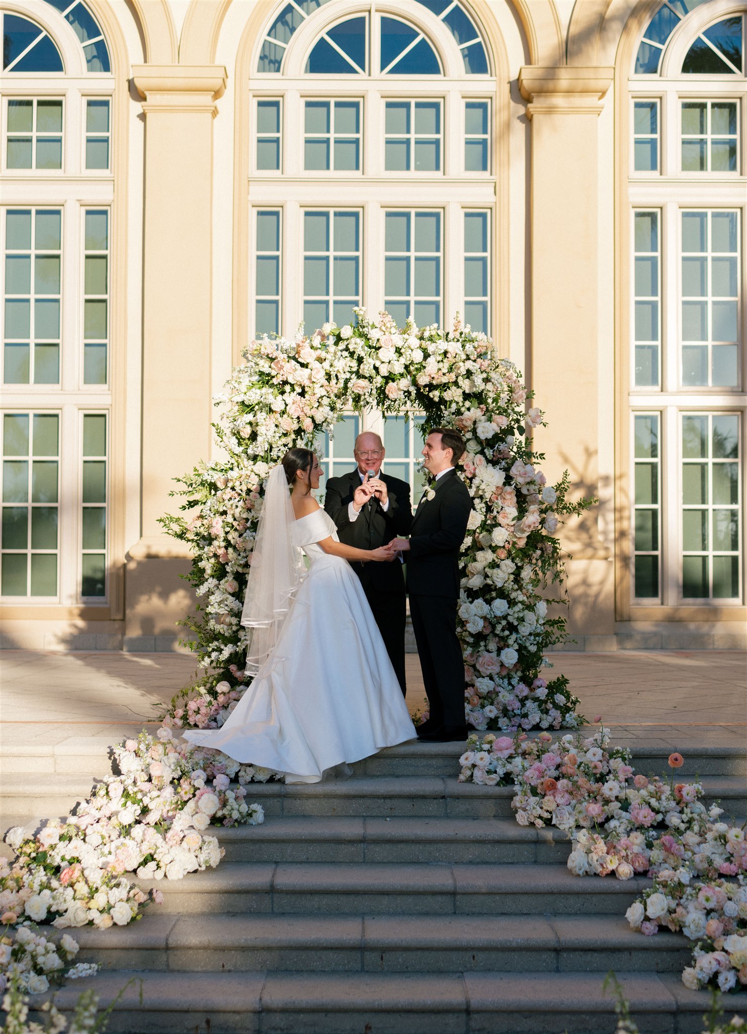 A couple holds hands under their ceremony arch in Florida.
