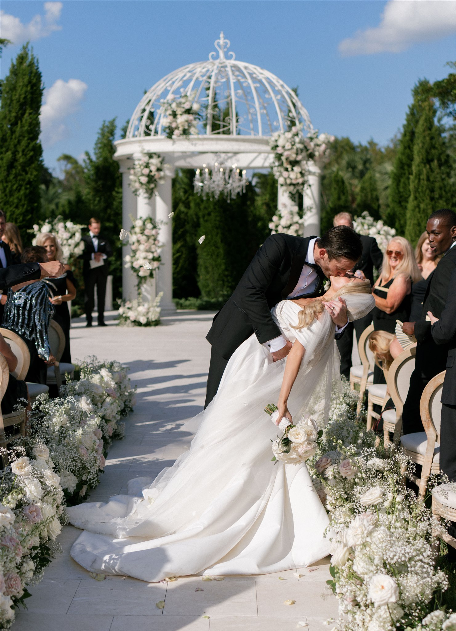 A bride and groom share a kiss as they exit their wedding ceremony.