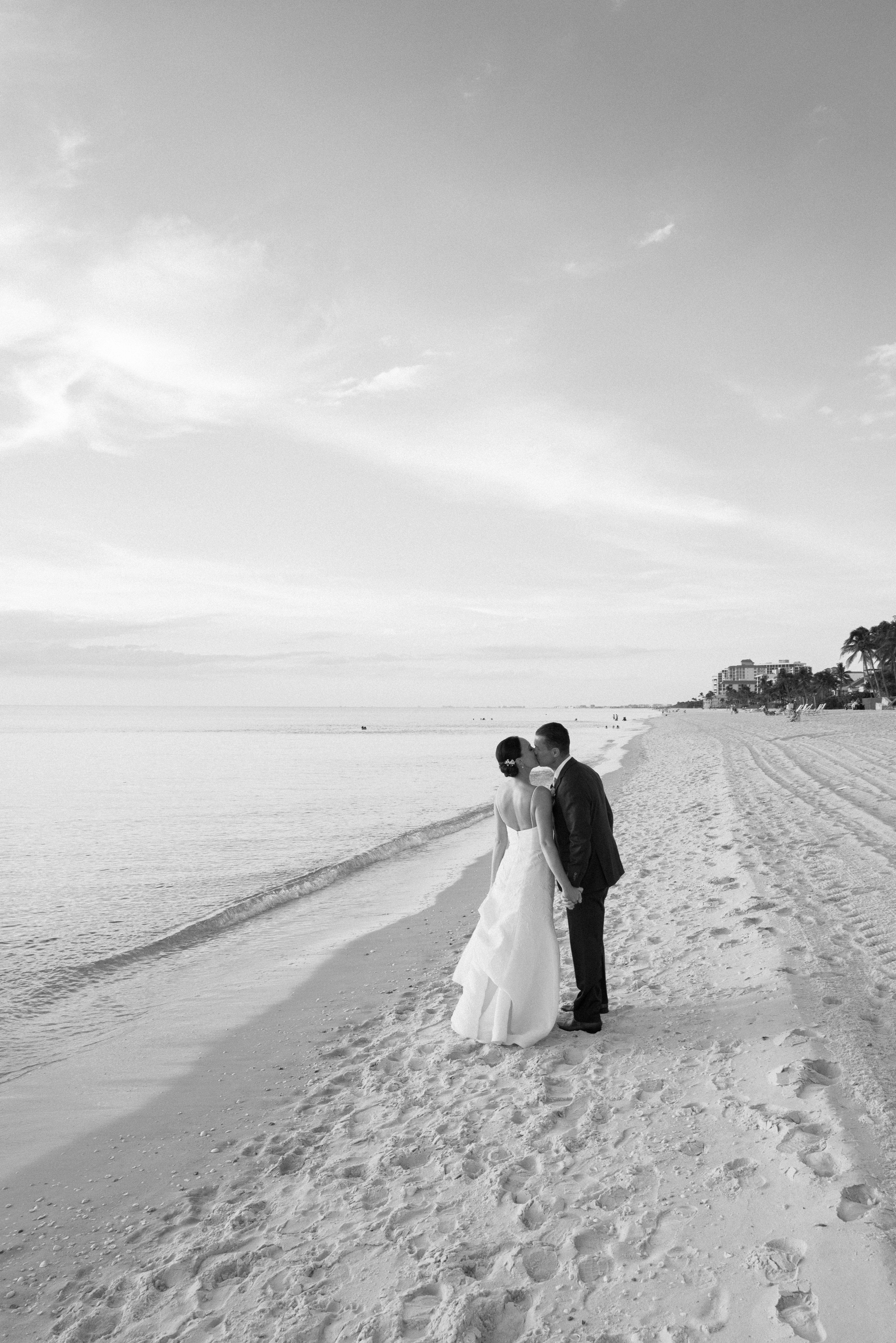A bride and groom share a kiss on the beach in Florida during their wedding portraits.