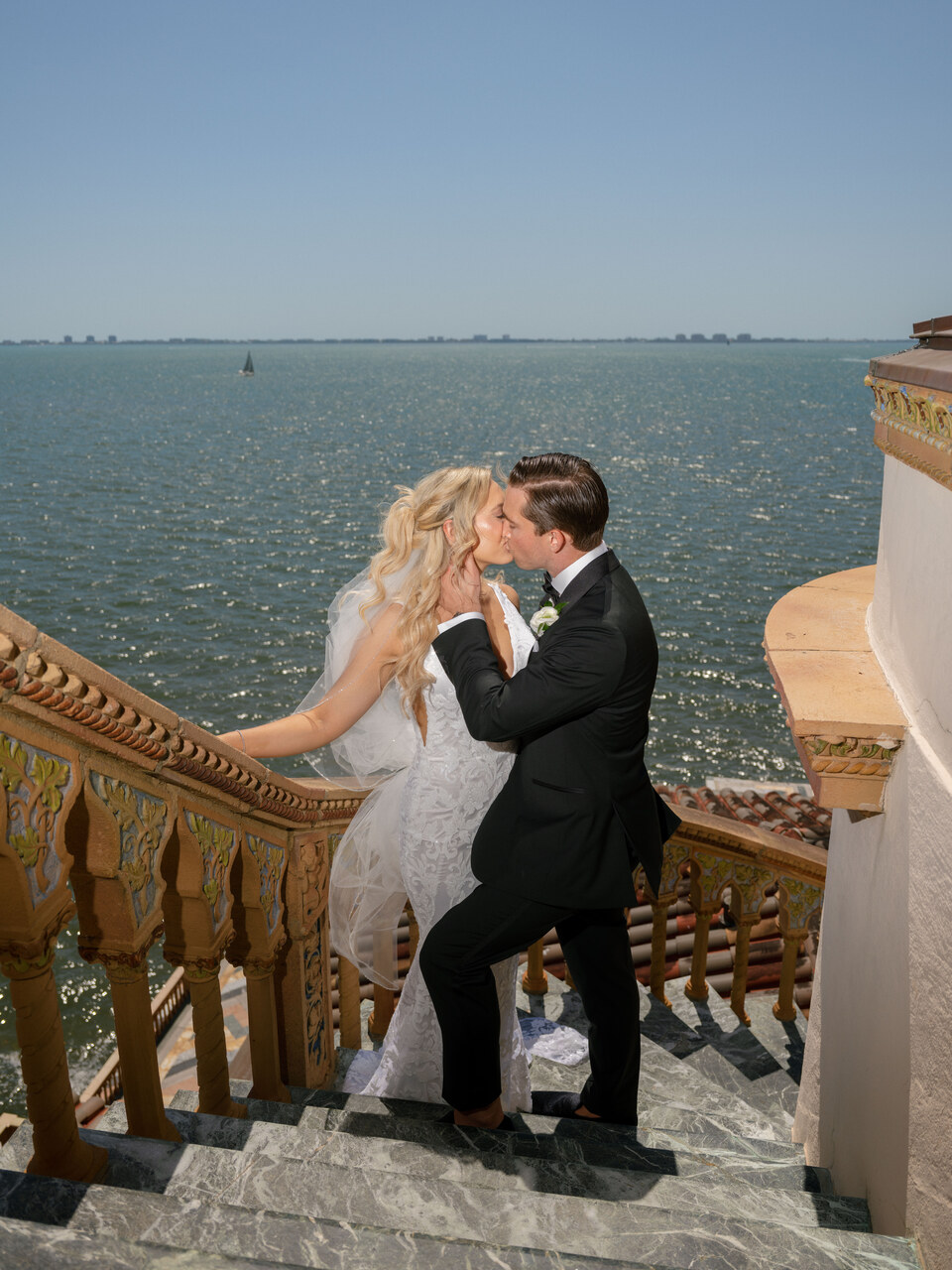 A couple sharing a kiss on their wedding day on the steps of The Ringling in Florida.