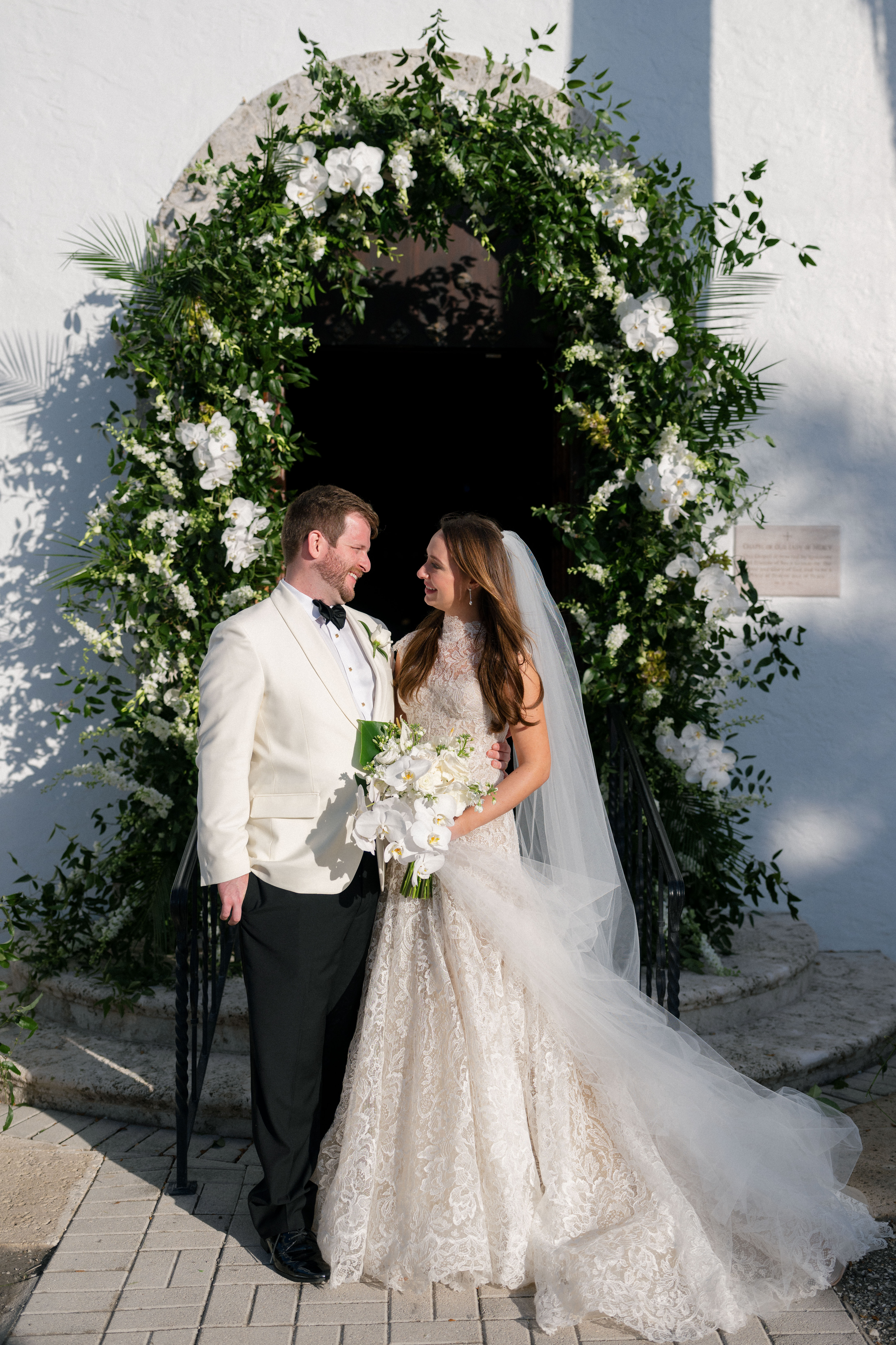 A bride and groom under their wedding floral arch.
