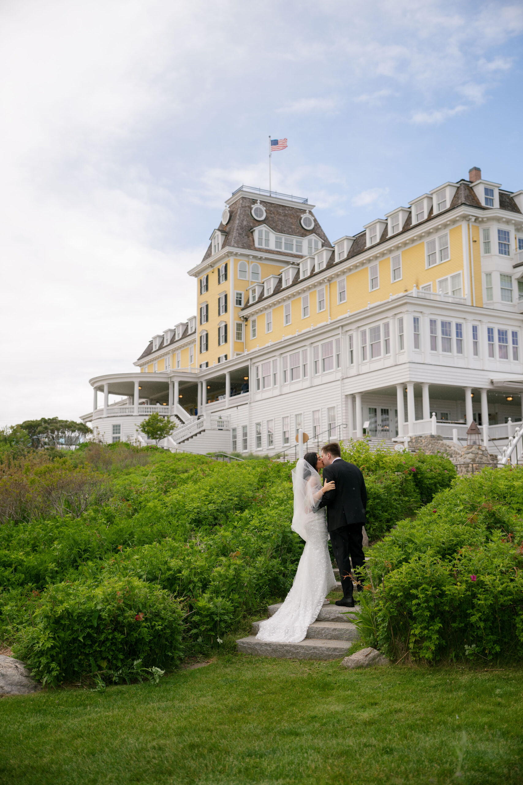 A bride and groom sharing a kiss in front of the Ocean House Rhode Island property.