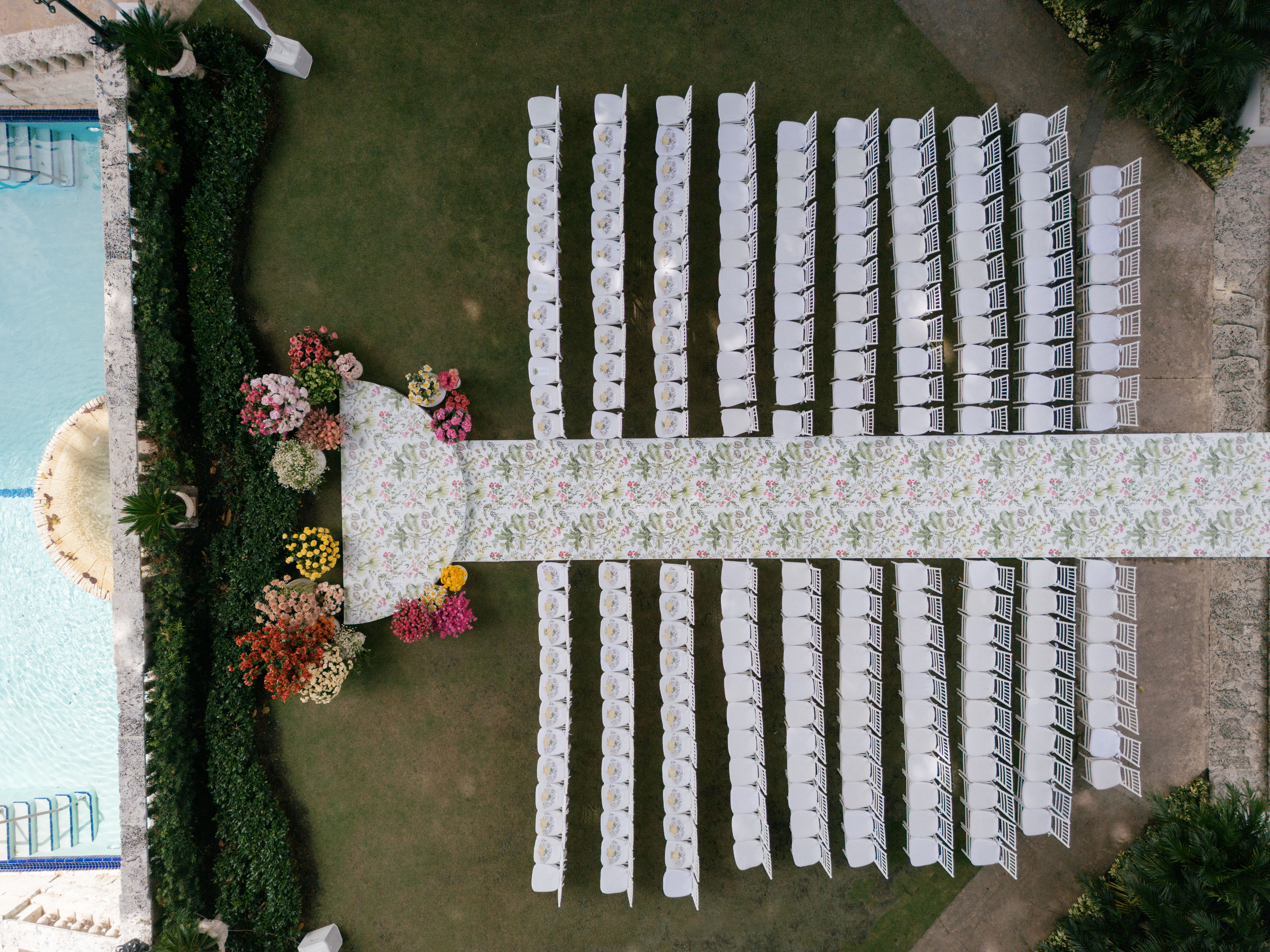 Aerial view of a ceremony with white chairs and colorful flowers.