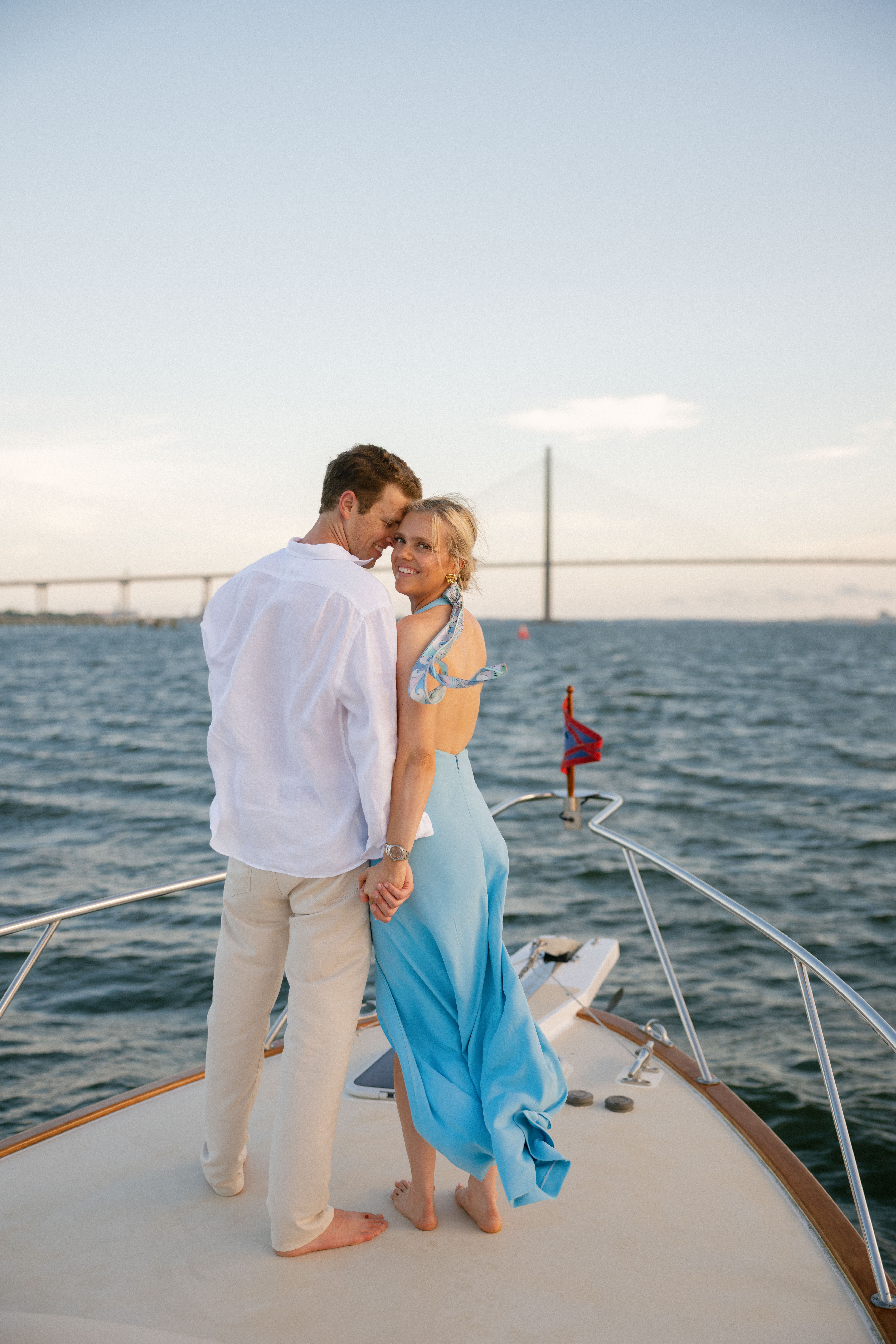 A couple posing for engagement portraits on the deck of a boat in Charleston.