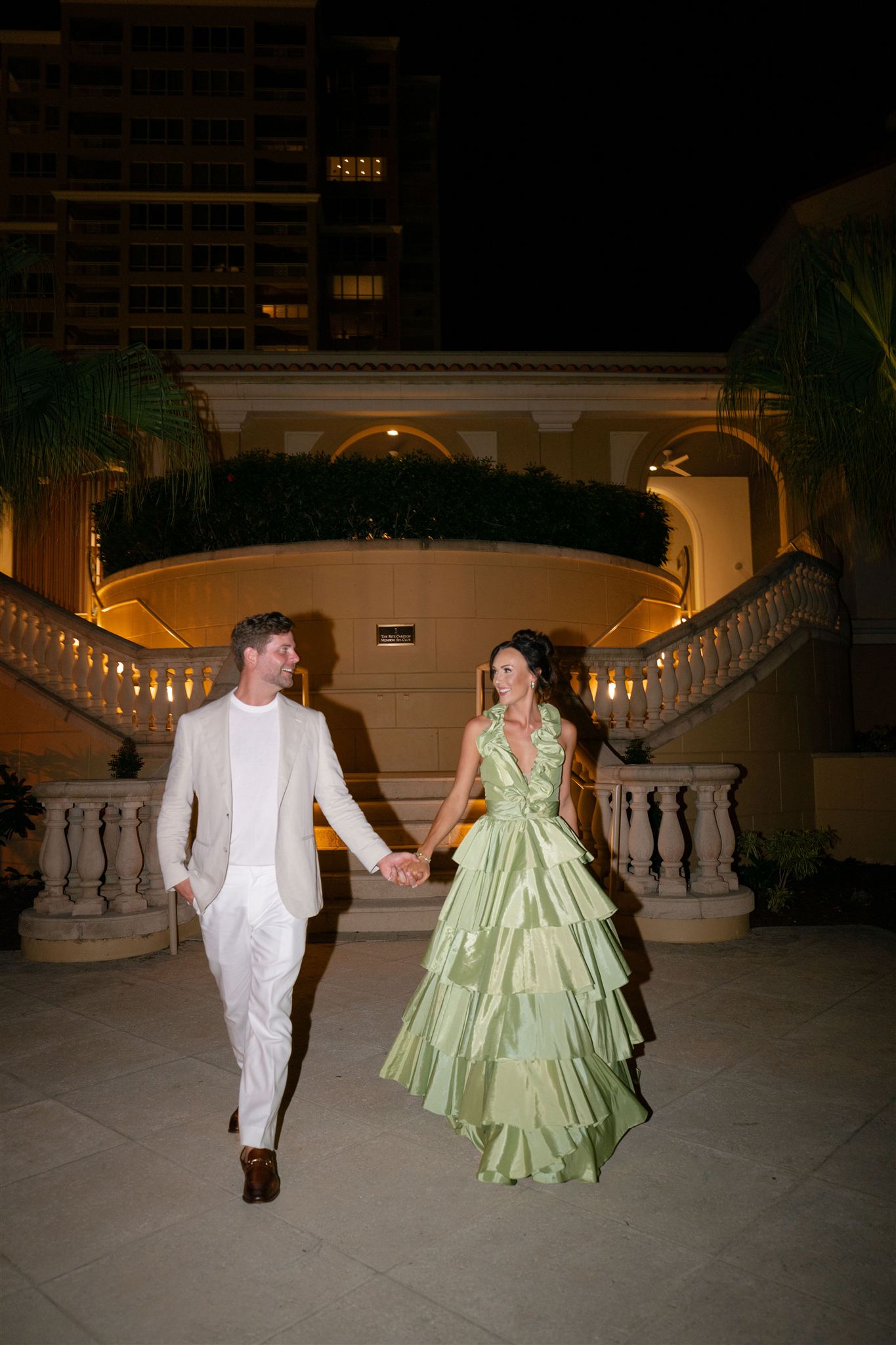 A bride and groom walk hand in hand for night time portraits at the Ritz Carlton Sarasota.