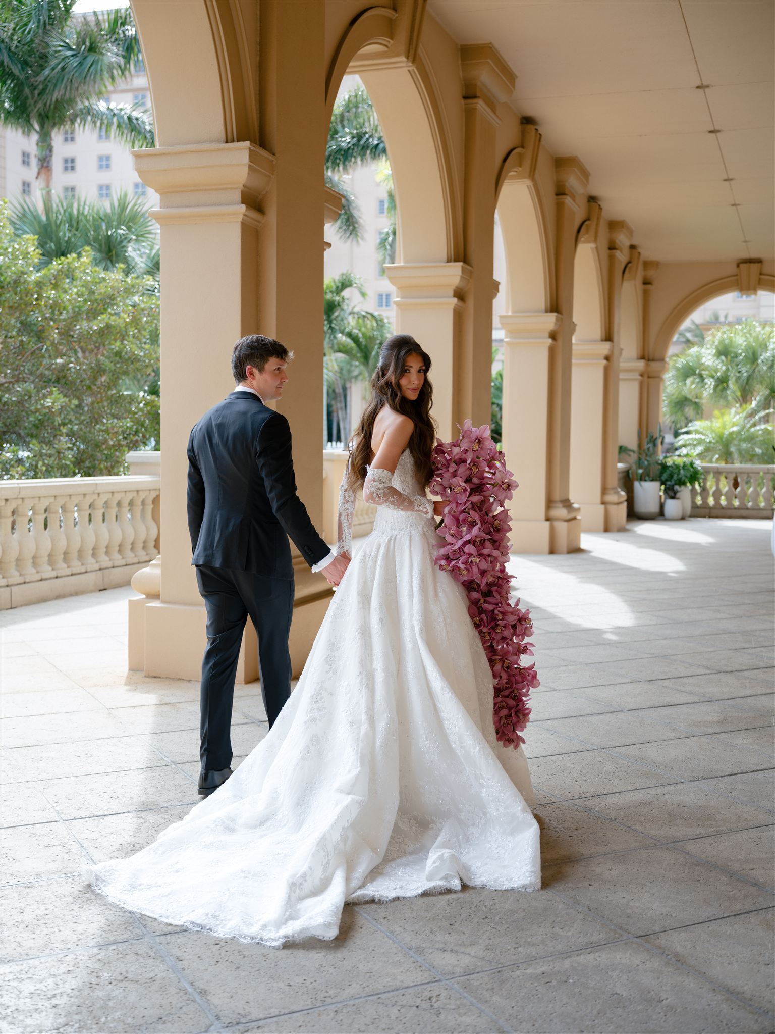 Bride and groom walking beneath arches at the Ritz-Carlton Naples.