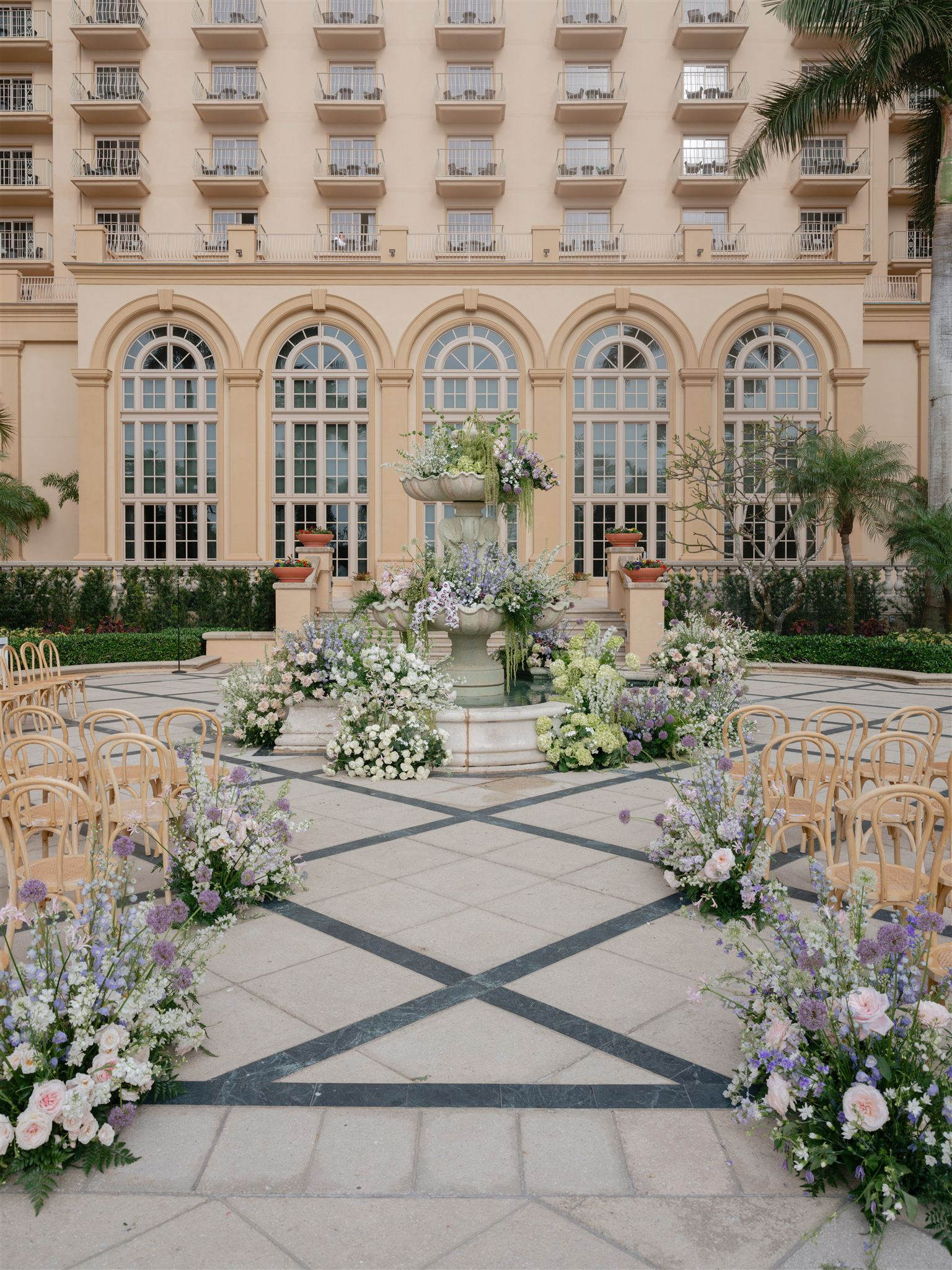 Ritz-Carlton Naples Beach wedding ceremony on the stone patio with lush floral arrangements surrounding a water fountain.