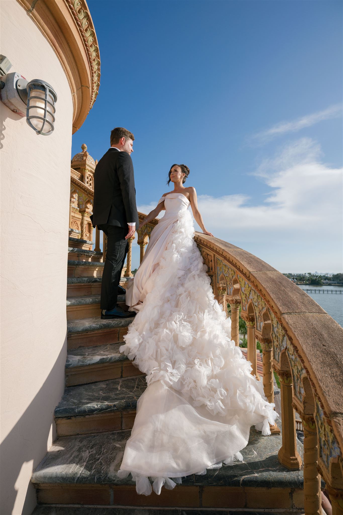 A bride and groom pose on the stairs of The Ringling Museum.