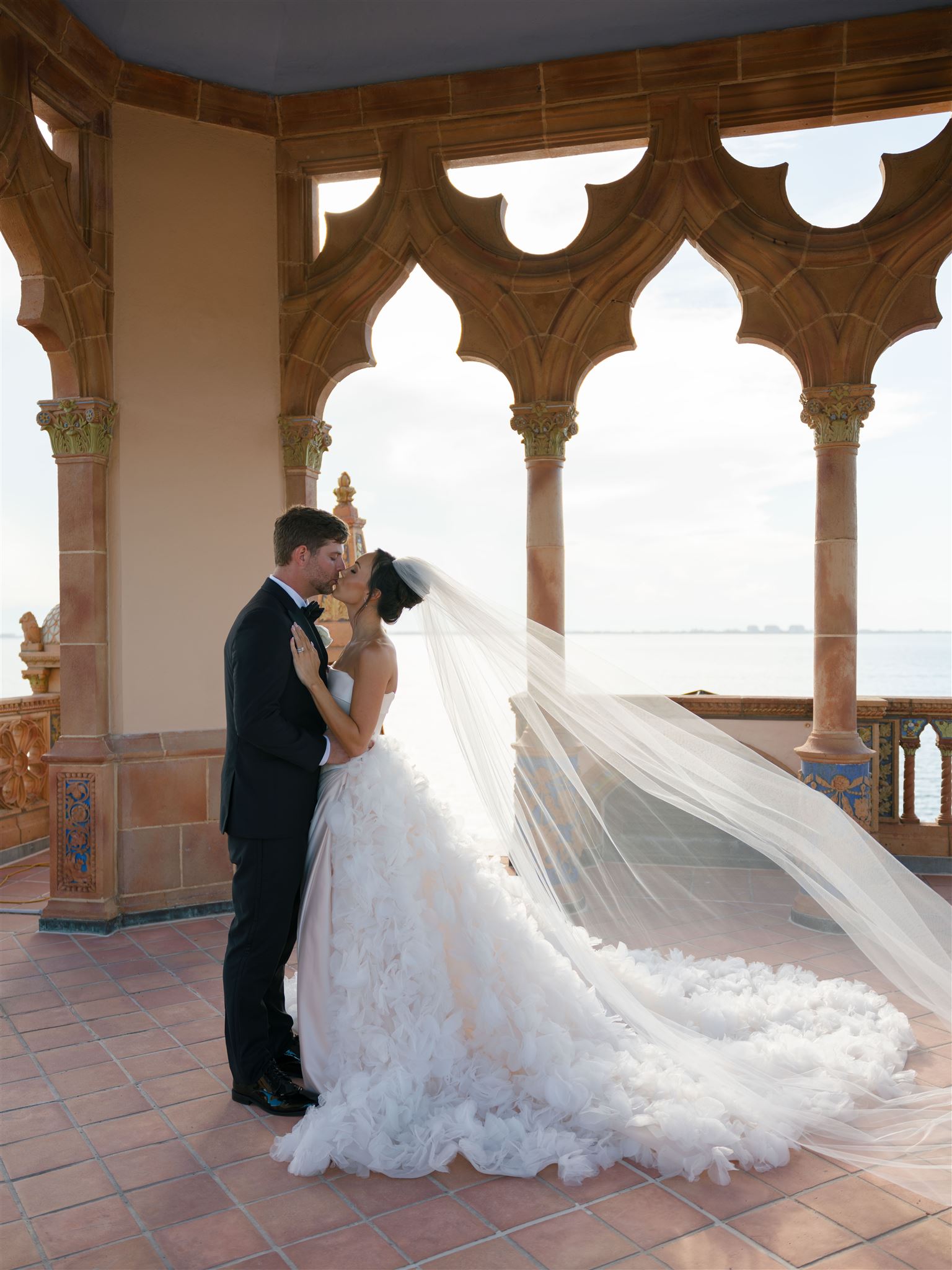 A bride and groom kissing during portraits at The Ringling, the bride's veil trailing behind her.