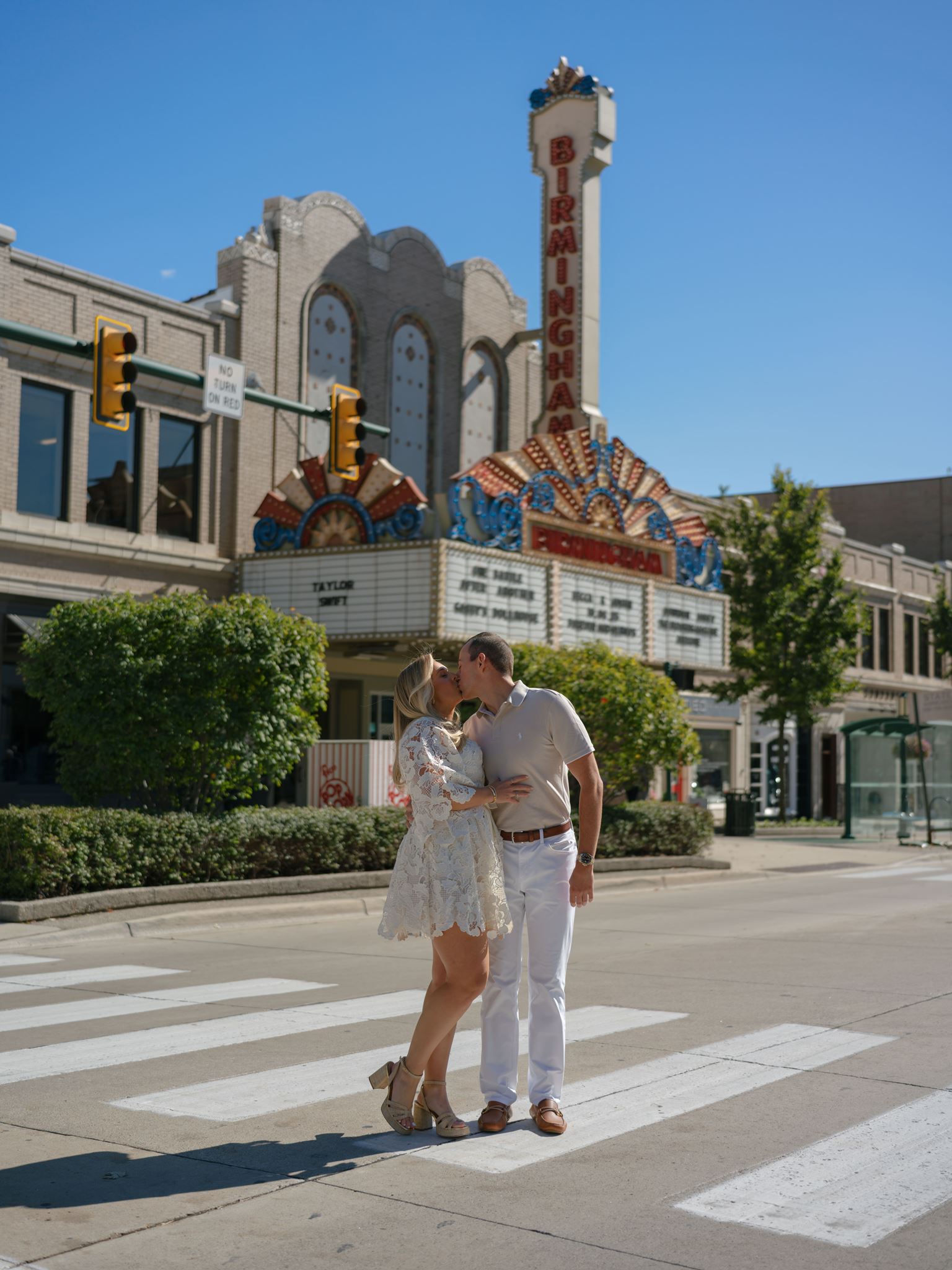 A couple kissing in the street in front of a local theater for their engagement photos.