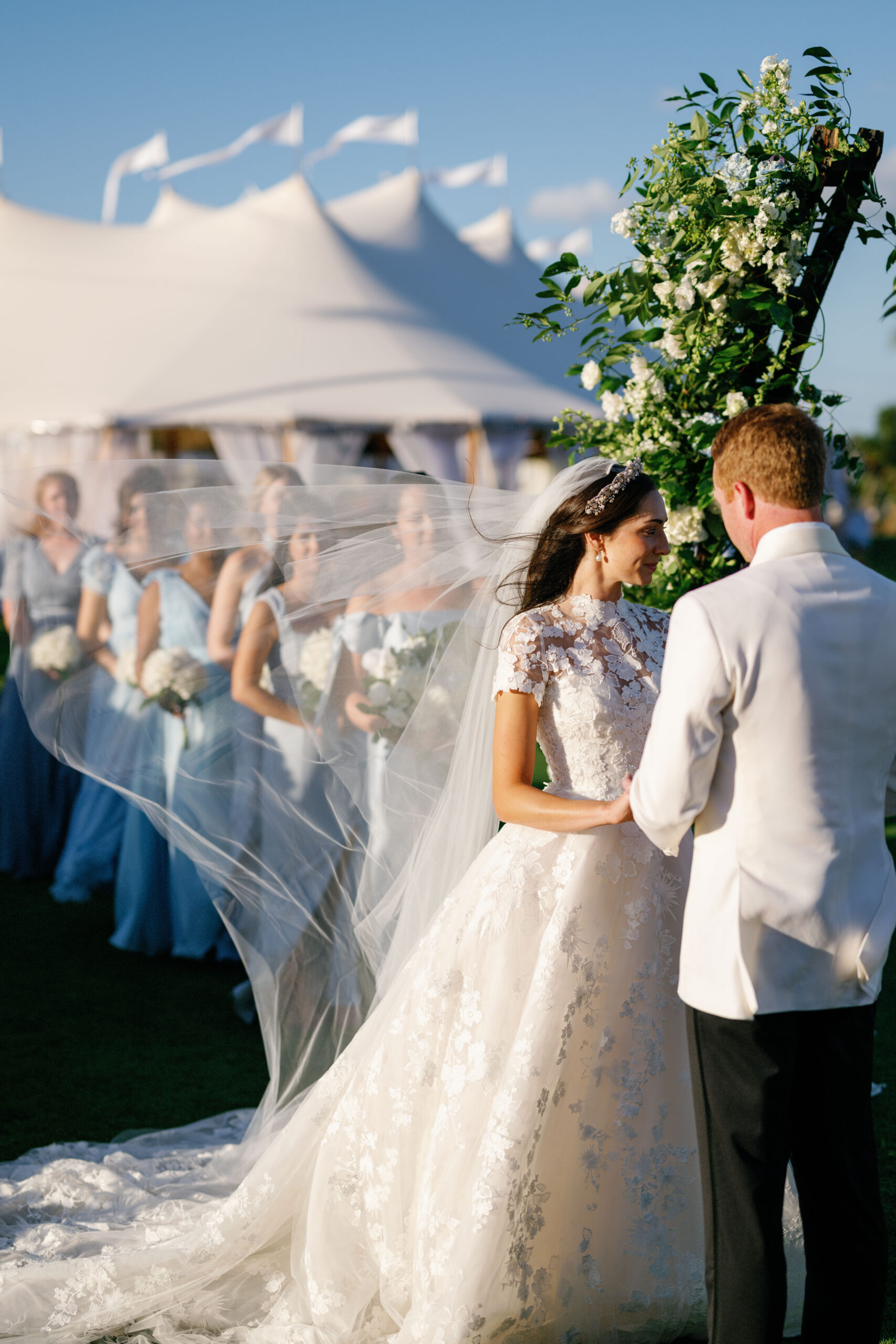 A bride and groom exchanging vows at the altar in front of a floral arch.