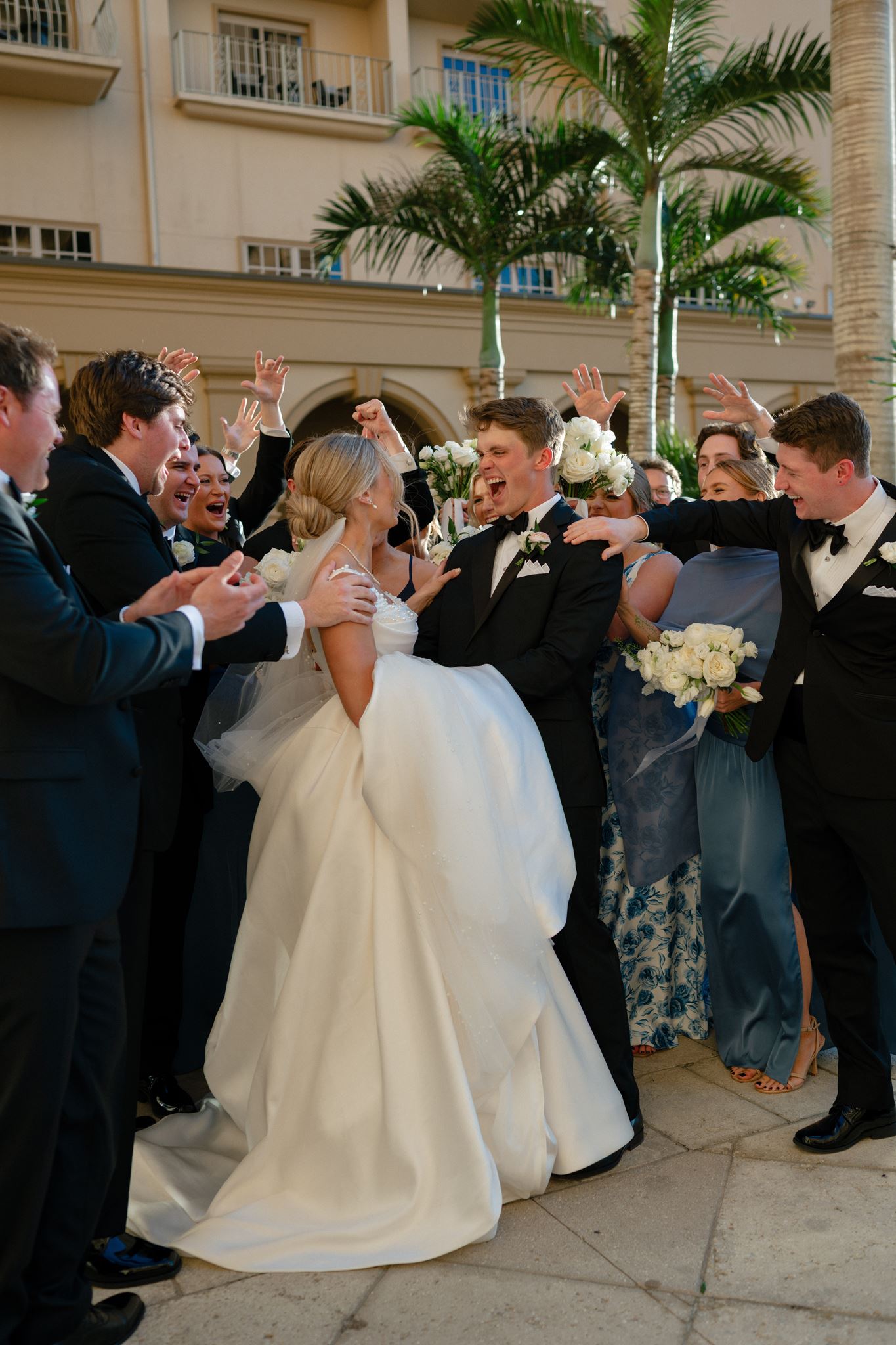 A bride and groom surrounded by guests as they walk back down the outdoor aisle.