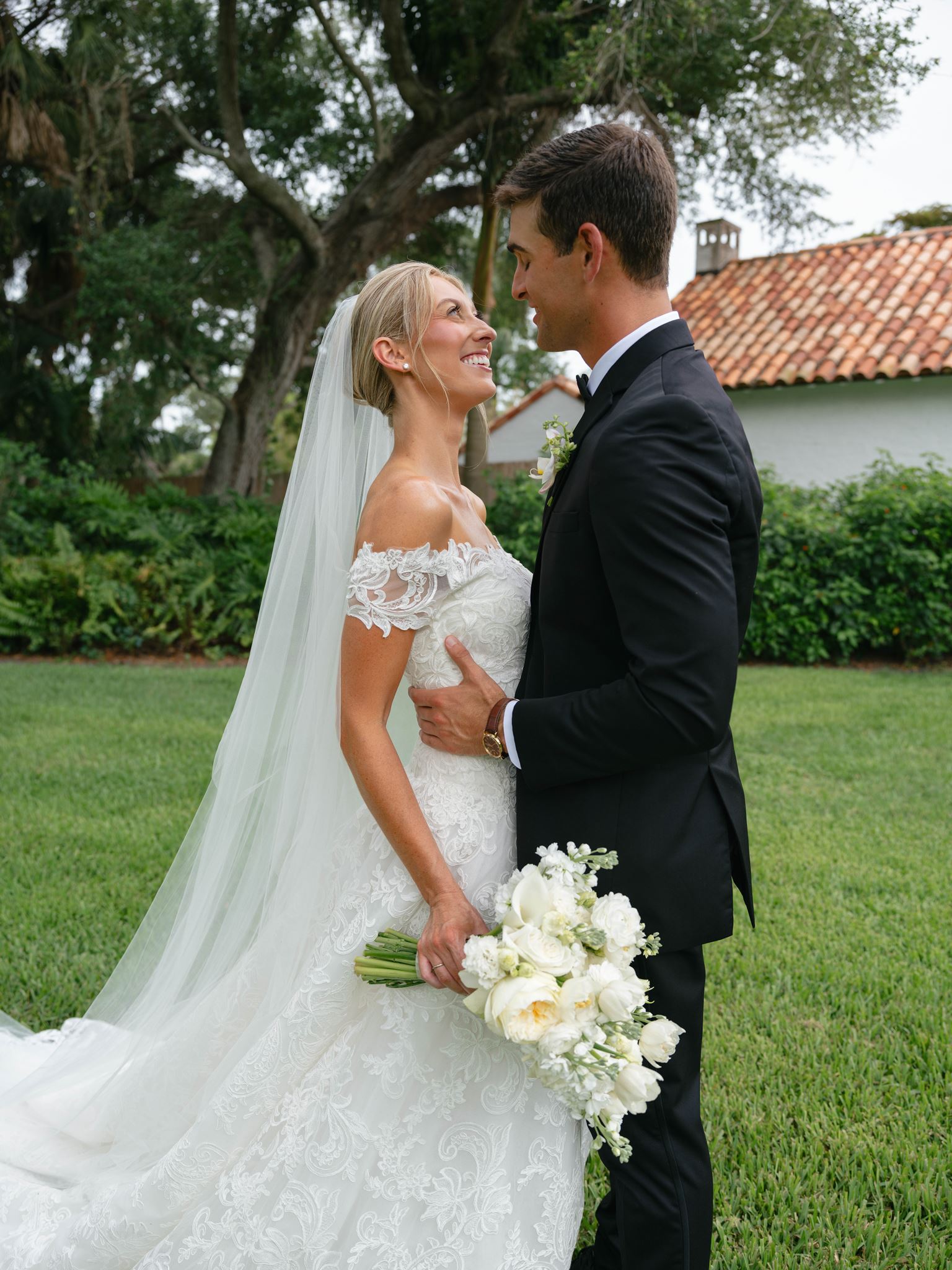 A bride and groom pose for portraits outside of their wedding venue, The Field Club in Sarasota, Florida.