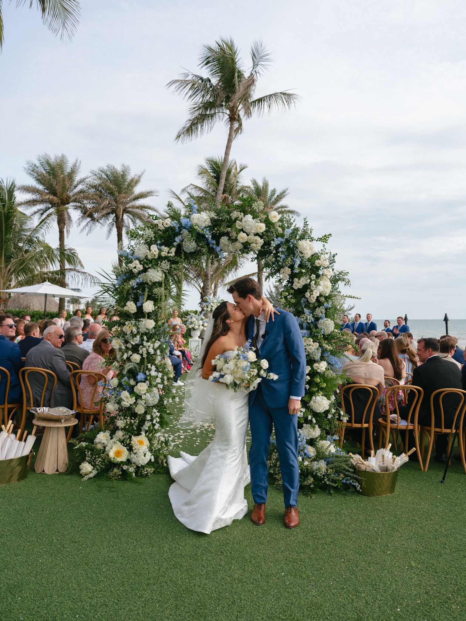 Bride and groom kissing at the end of their outdoor aisle.